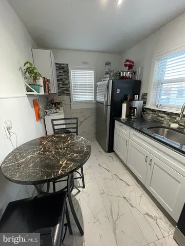 a kitchen with stainless steel appliances granite countertop a sink white cabinets and a refrigerator