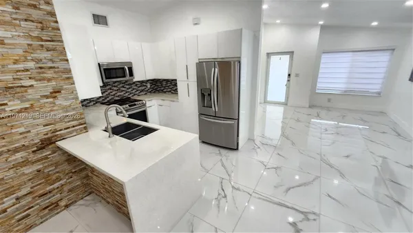 a white kitchen with a stove top oven and sink