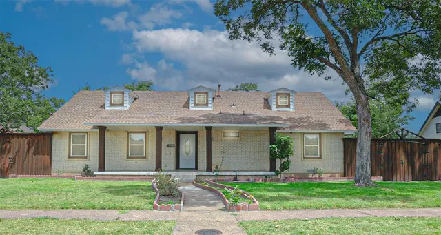 a front view of a house with a garden and trees