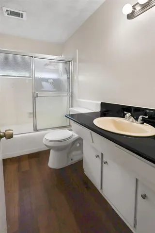 a bathroom with a granite countertop sink a toilet a mirror and shower