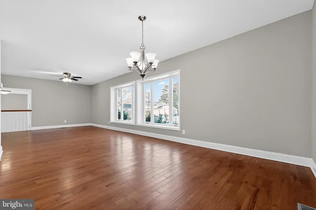 a view of an empty room with wooden floor kitchen and a window