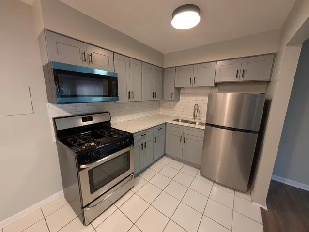 a kitchen with white cabinets a sink a stove a microwave and a refrigerator