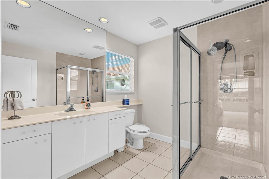 13005 Harbour Ridge Boulevard Palm City, FL 34990 - Photo 22 of 40 a bathroom with a double vanity sink toilet mirror and shower