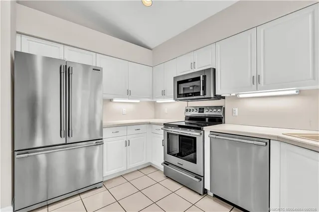 a kitchen with cabinets stainless steel appliances and a refrigerator