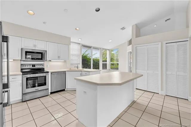 a kitchen with stainless steel appliances a sink a stove a microwave a counter top space and cabinets