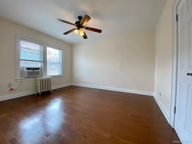 an empty room with wooden floor fan and windows