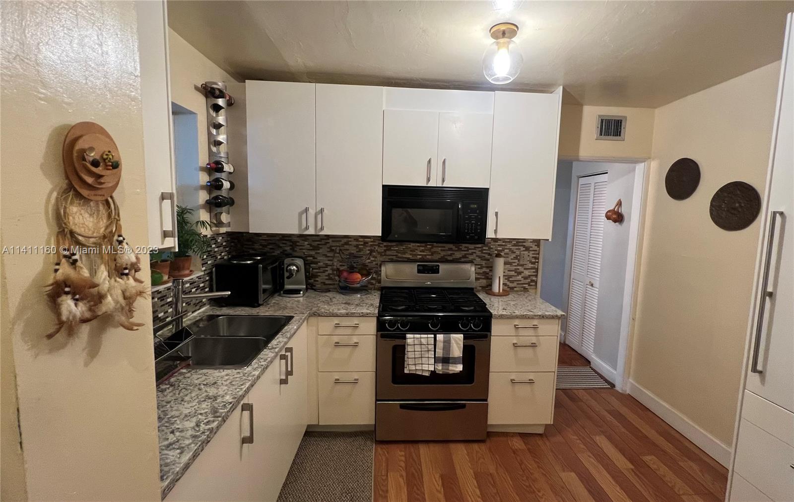 342 Southwest 29th Road Miami, FL 33129 - Photo 10 of 28 a kitchen with stainless steel appliances kitchen island granite countertop a stove a sink and a refrigerator