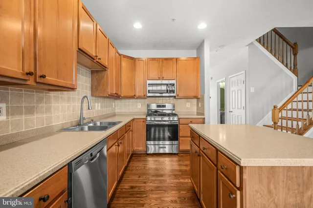 a kitchen with stainless steel appliances granite countertop a sink a stove and a refrigerator