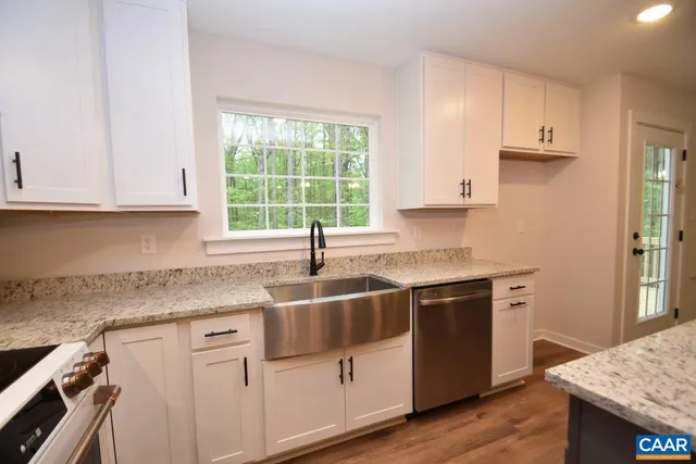 a kitchen with granite countertop a sink stove and cabinets