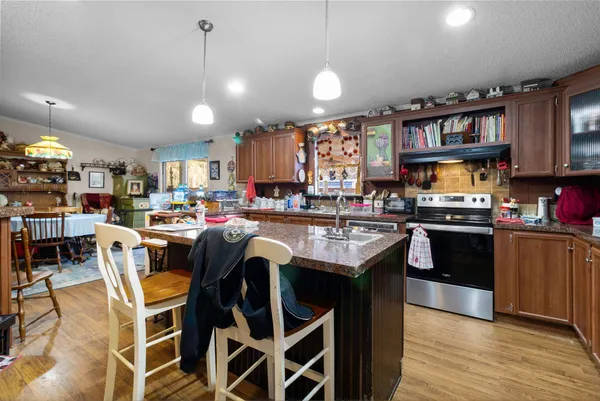 a kitchen with stainless steel appliances granite countertop a stove a sink dishwasher and a refrigerator with wooden floor