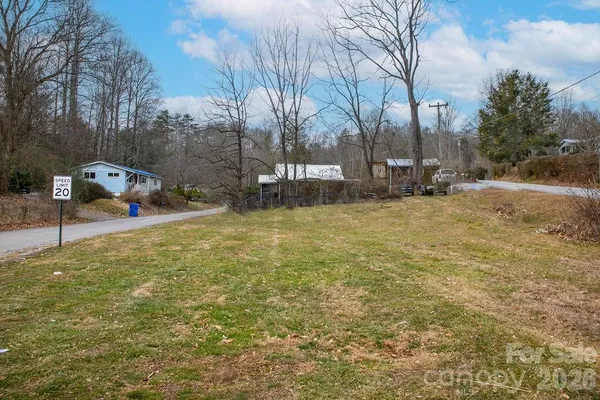 a view of a yard with a house and trees in the background