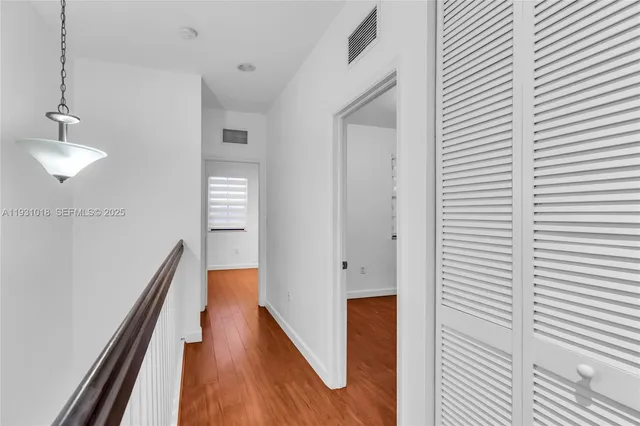 a hallway with wooden floor electronic appliances and stairs