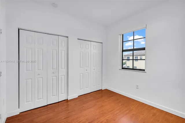 an empty room with wooden floor closet and windows