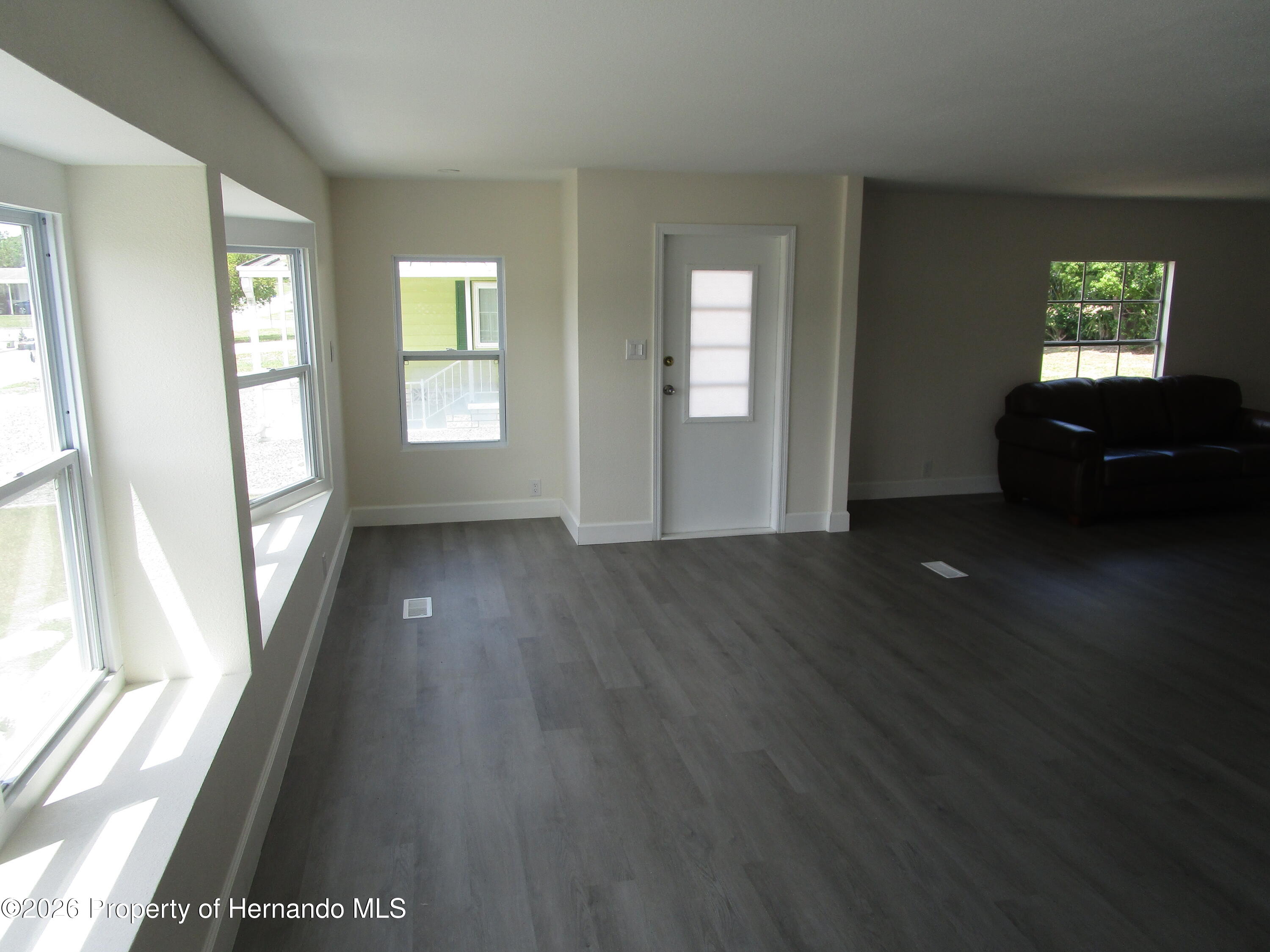 14790 Rialto Avenue, Unit 3 Brooksville, FL 34613 - Photo 4 of 15 wooden floor in an empty room with a window