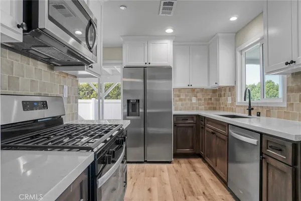 a kitchen with kitchen island granite countertop a sink stainless steel appliances and cabinets