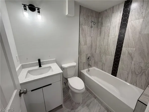 a bathroom with a sink a toilet a tub and shower