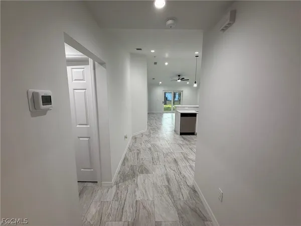 a view of a hallway with wooden floor and a bathroom