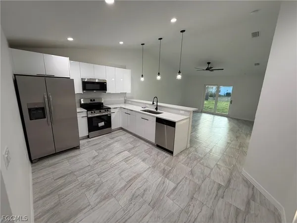 a kitchen with stainless steel appliances a refrigerator a sink a stove a microwave a center island and furniture