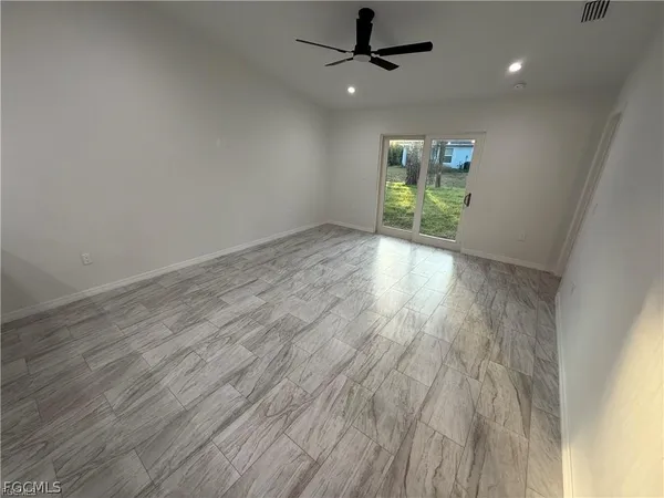 an empty room with wooden floor fan and windows