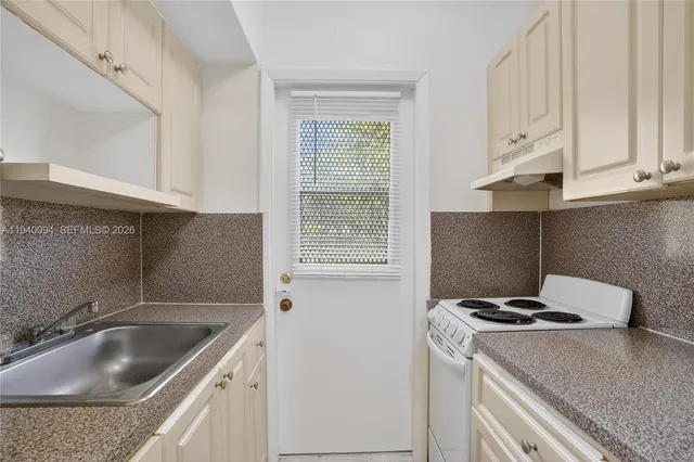 a kitchen with granite countertop a sink stove and cabinets