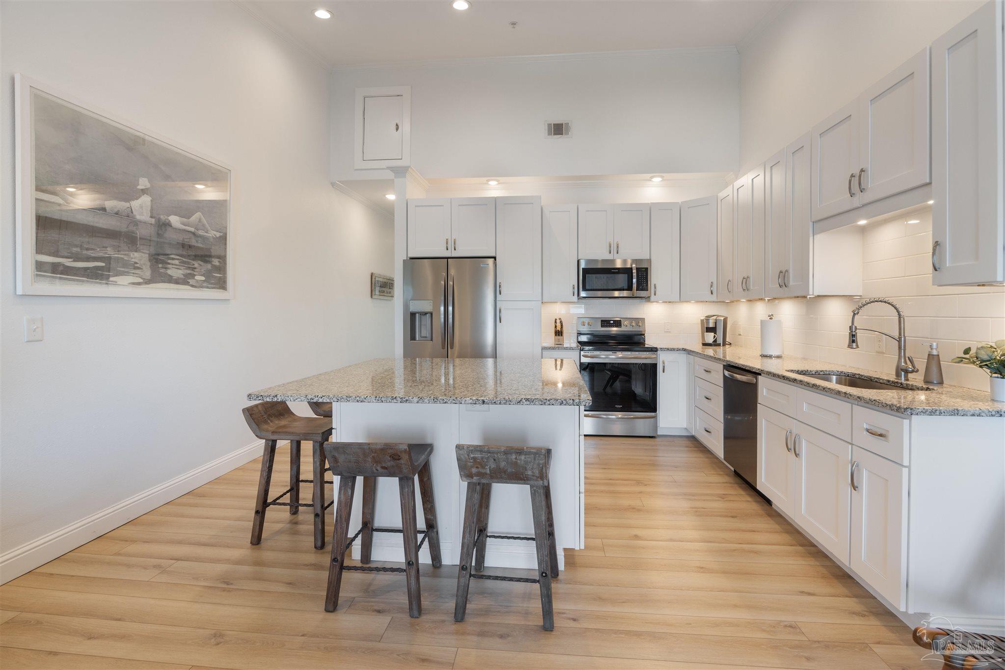 17290 Perdido Key Drive, Unit B2 Pensacola, FL 32507 - Photo 12 of 54 a kitchen with stainless steel appliances granite countertop a stove a sink a microwave a refrigerator white cabinets and wooden floor