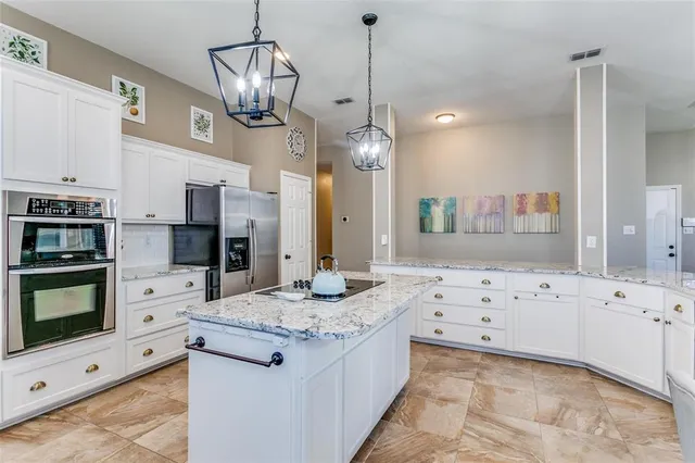 a kitchen with stainless steel appliances kitchen island granite countertop a stove a sink and a white cabinets