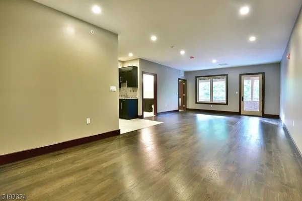 a view of an empty room with window and wooden floor