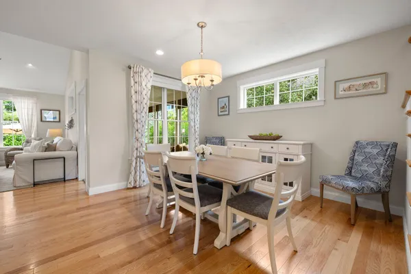 a dining room with wooden floor a chandelier a wooden table and chairs