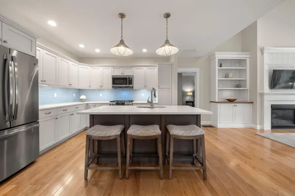 a kitchen with granite countertop a table chairs stainless steel appliances and wooden floor