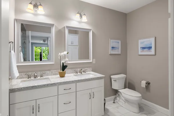 a bathroom with a granite countertop toilet sink and mirror