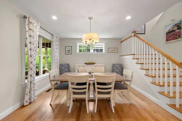 a dining room with wooden floor a chandelier a wooden table and chairs