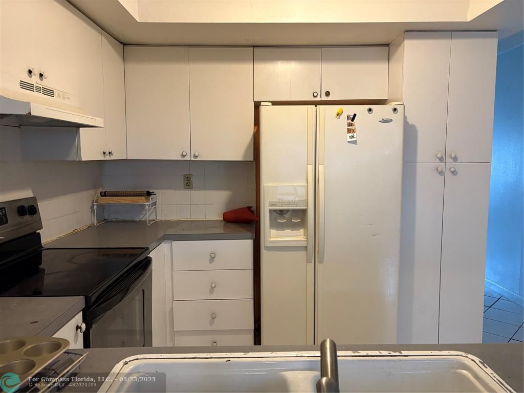 7659 Northwest 74th Avenue Tamarac, FL 33321 - Photo 6 of 11 a kitchen with a refrigerator and white cabinets