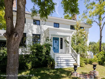 a view of a house with potted plants and a fountain