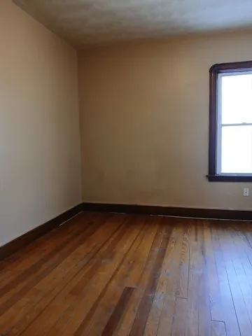 a view of an empty room and wooden floor and window