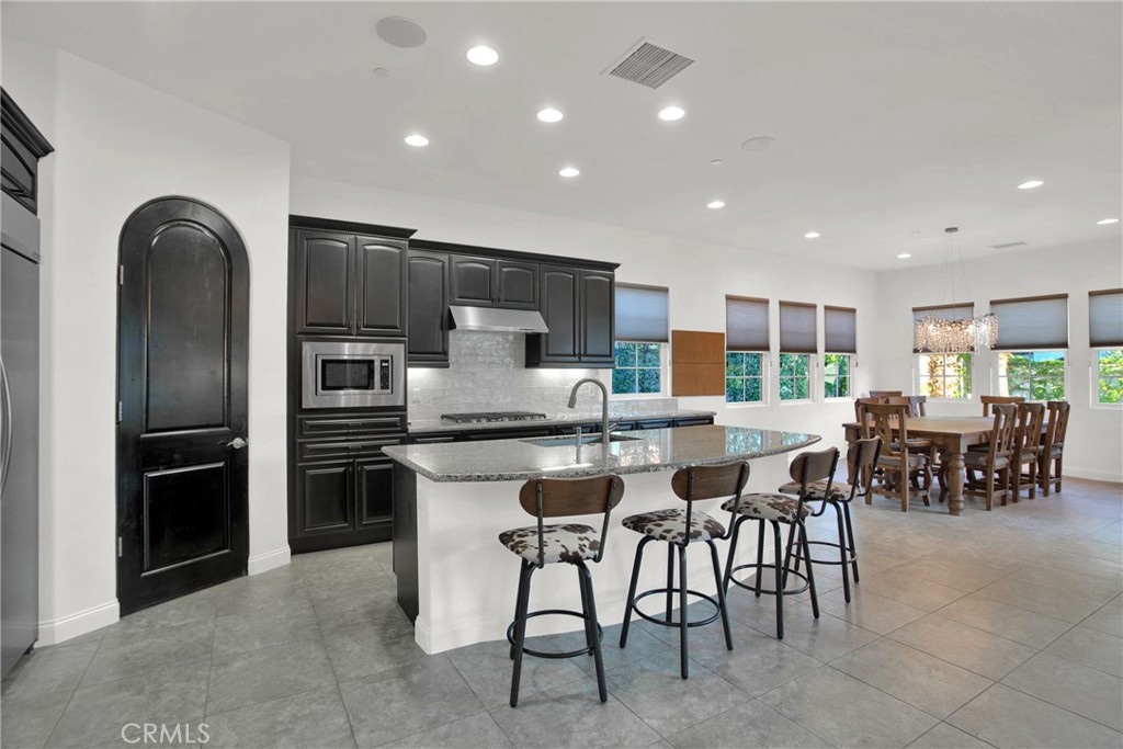 6 Cassis Circle Rancho Mirage, CA 92270 - Photo 32 of 74 a kitchen with stainless steel appliances kitchen island granite countertop a table and chairs