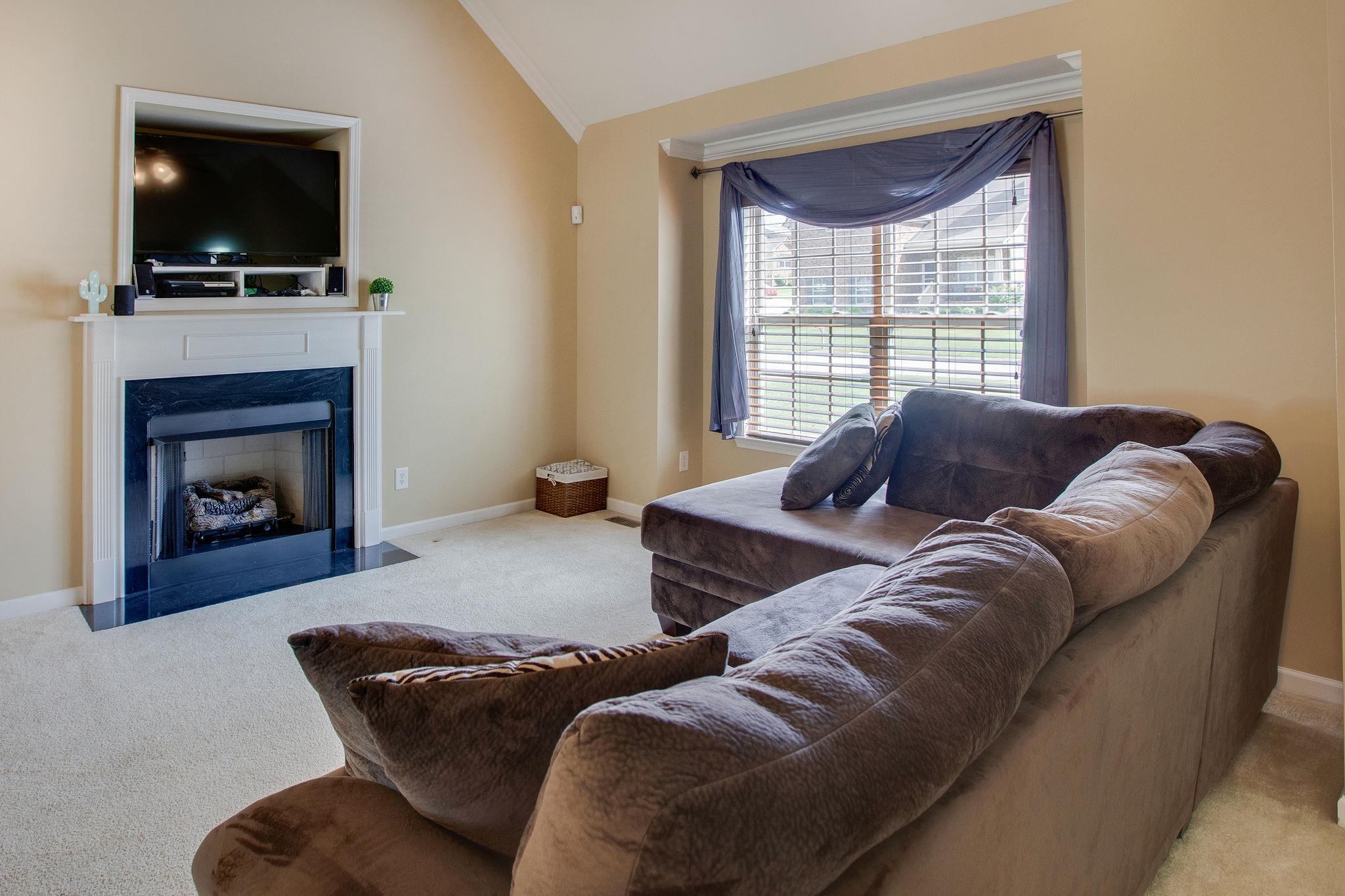 1046 Golf View Way Spring Hill, TN 37174 - Photo 6 of 22 a living room with furniture a flat screen tv and a fireplace