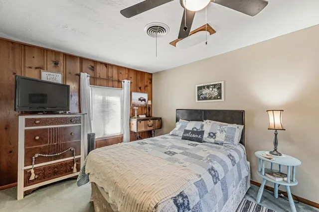 a bedroom with a bed and a flat tv screen on wall