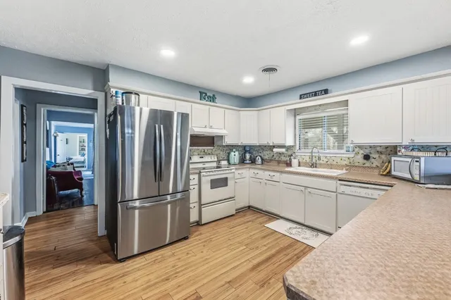 a kitchen with granite countertop stainless steel appliances a refrigerator cabinets and wooden floor