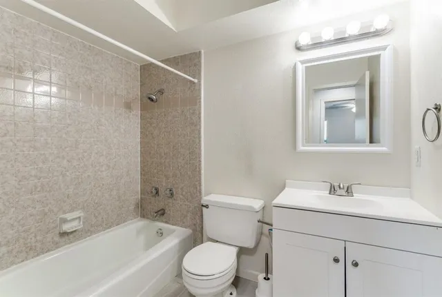 a bathroom with a toilet sink vanity tub and shower