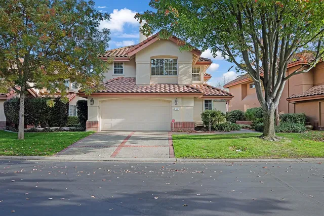 a front view of a house with a garden and trees