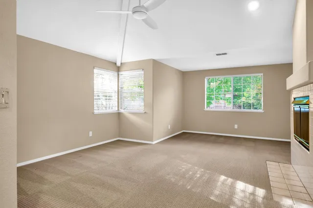 an empty room with windows and chandelier fan
