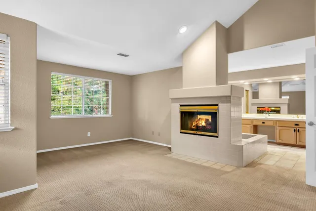 an empty room with windows fireplace and sink