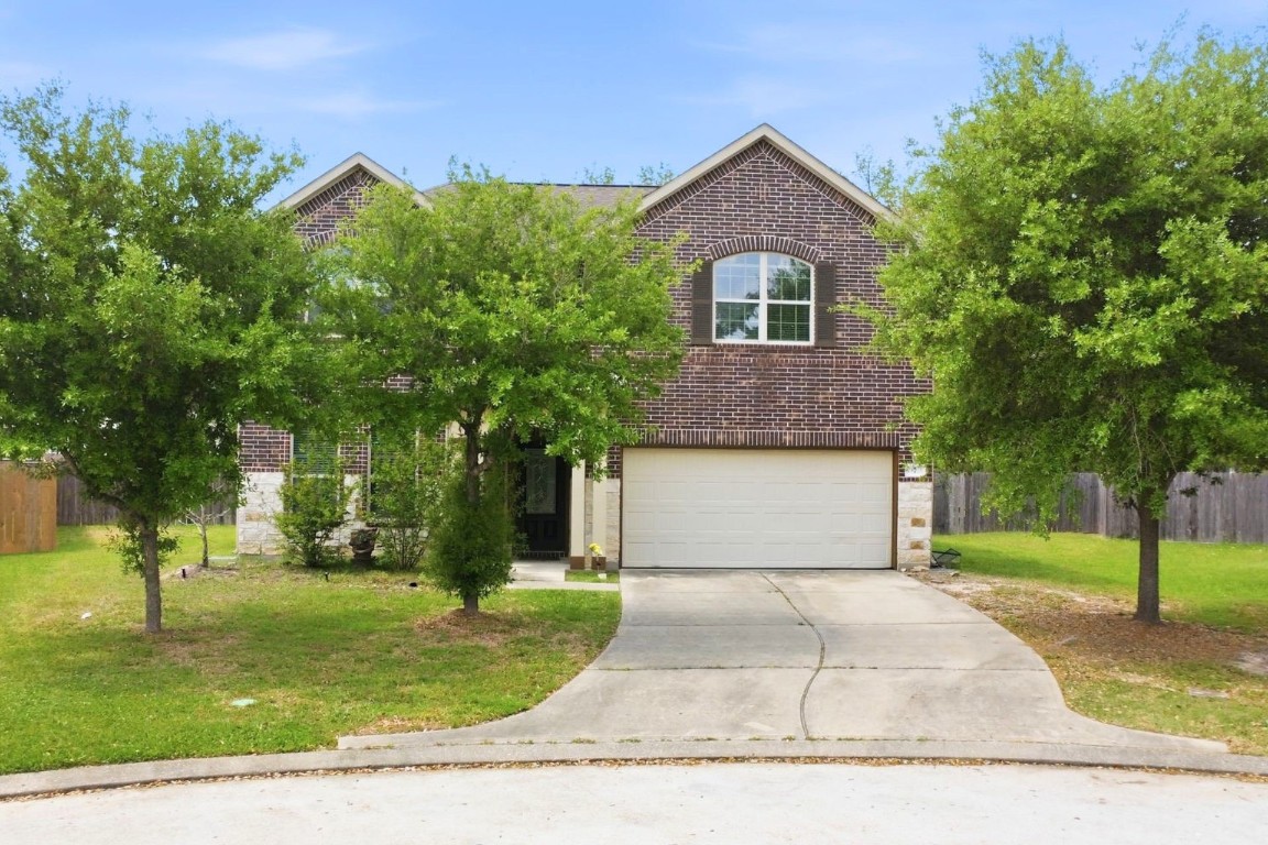7 Maple Mill Court Conroe, TX 77301 - Photo 2 of 20 a front view of a house with a garden and trees