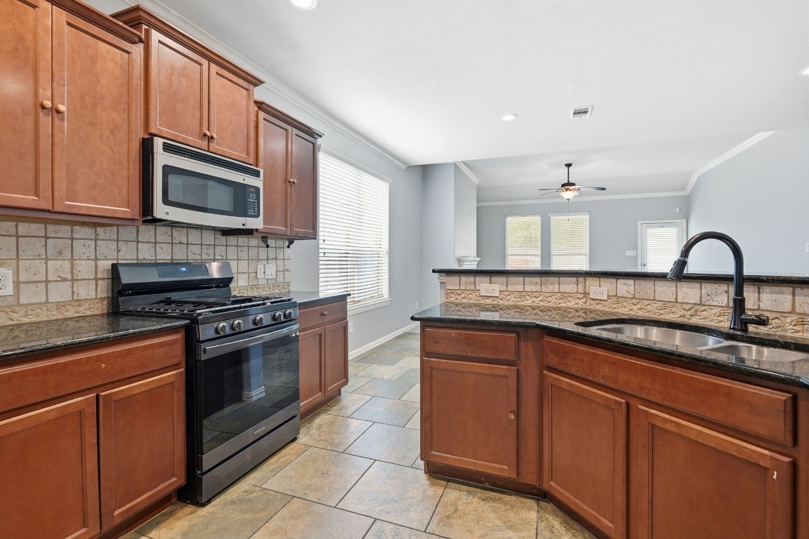 7 Maple Mill Court Conroe, TX 77301 - Photo 7 of 20 a kitchen with granite countertop a sink and stainless steel appliances