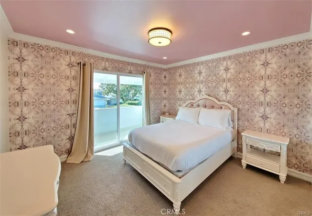 a bed sitting in a bedroom next to a window and a chandelier