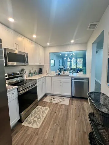 a kitchen with a sink wooden floor and stainless steel appliances