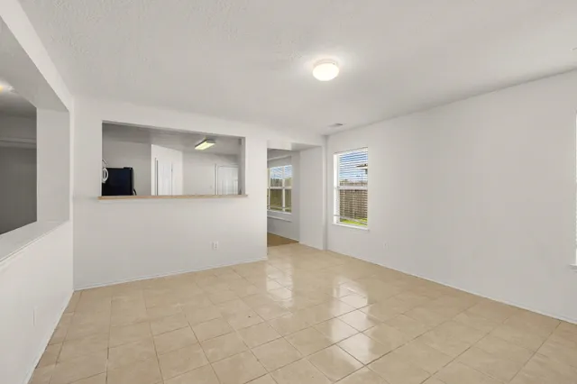 an empty room with a kitchen and natural light