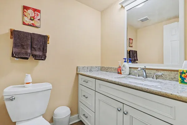 a bathroom with a granite countertop toilet sink and mirror