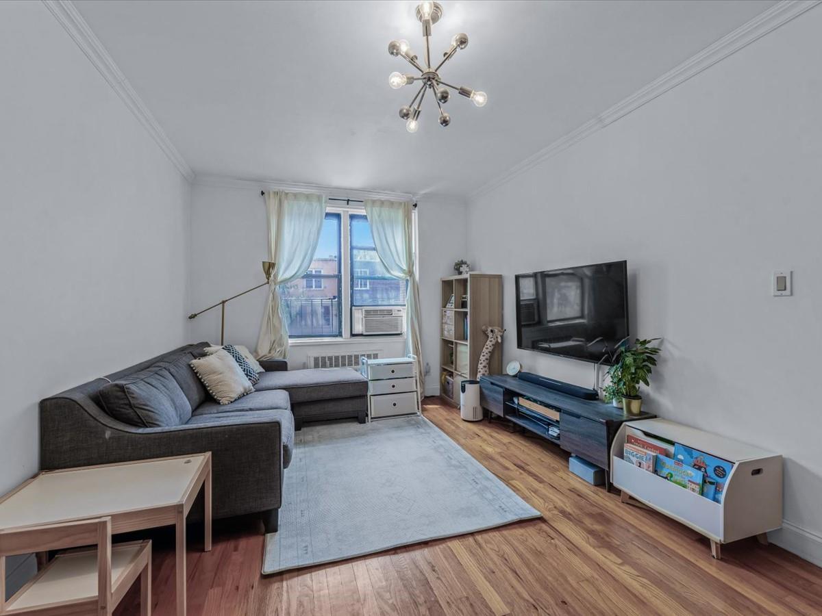 102-12 65th Avenue, Unit D22 Queens, NY 11375 - Photo 3 of 12 a living room with furniture and a flat screen tv