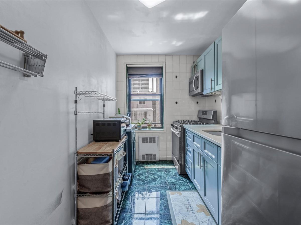 102-12 65th Avenue, Unit D22 Queens, NY 11375 - Photo 6 of 12 a kitchen with a stove a sink and a refrigerator